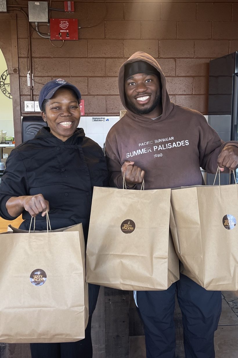 a man and woman holding food bags at restaurant