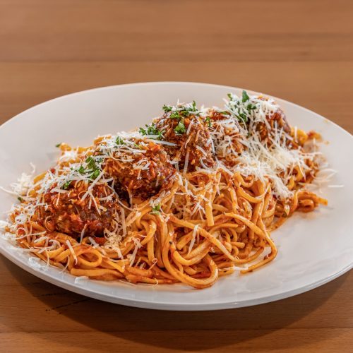 a plate of spaghetti with meatballs and grated cheese