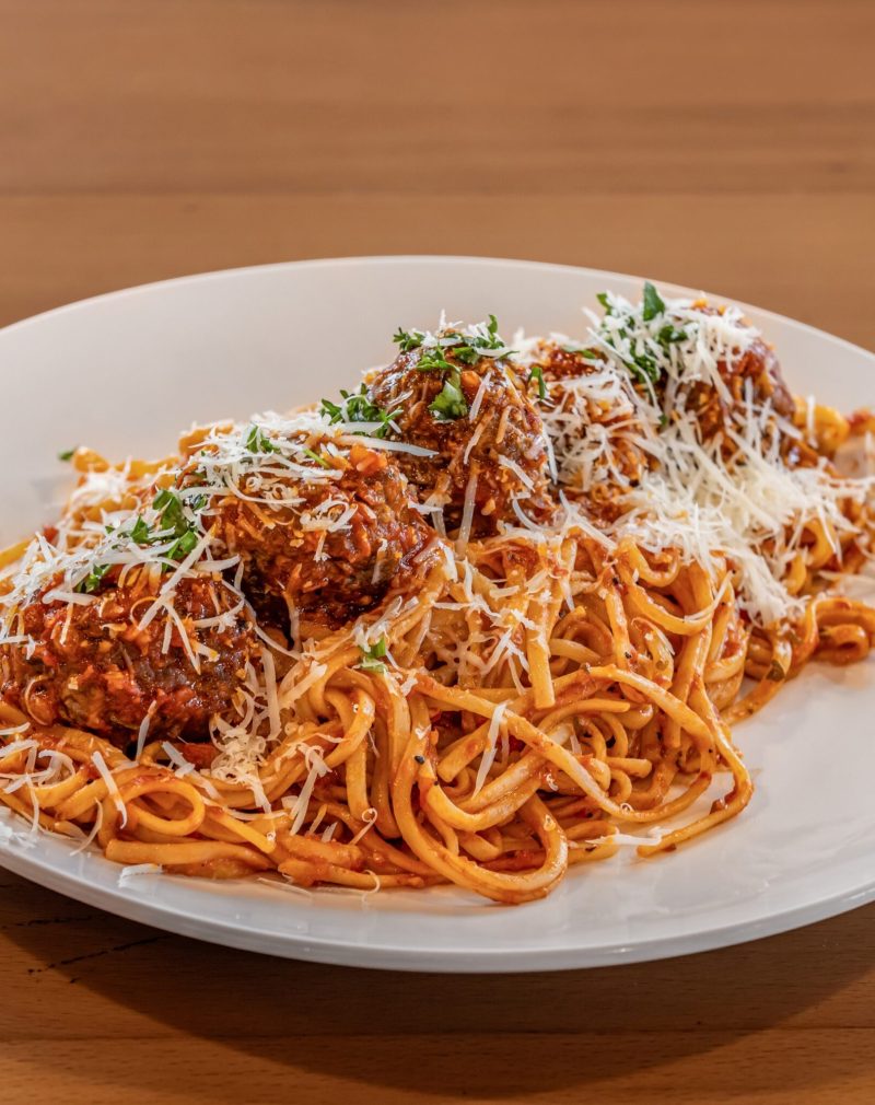 a plate of spaghetti with meatballs and grated cheese